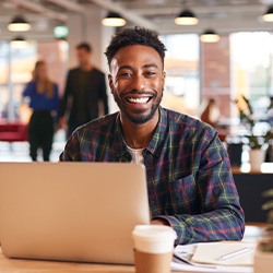 Man smiling while working on laptop in office