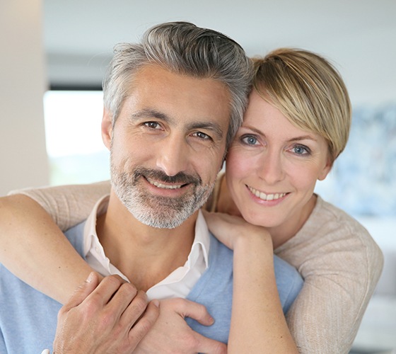 Man and woman smiling after metal free dental restoration placement